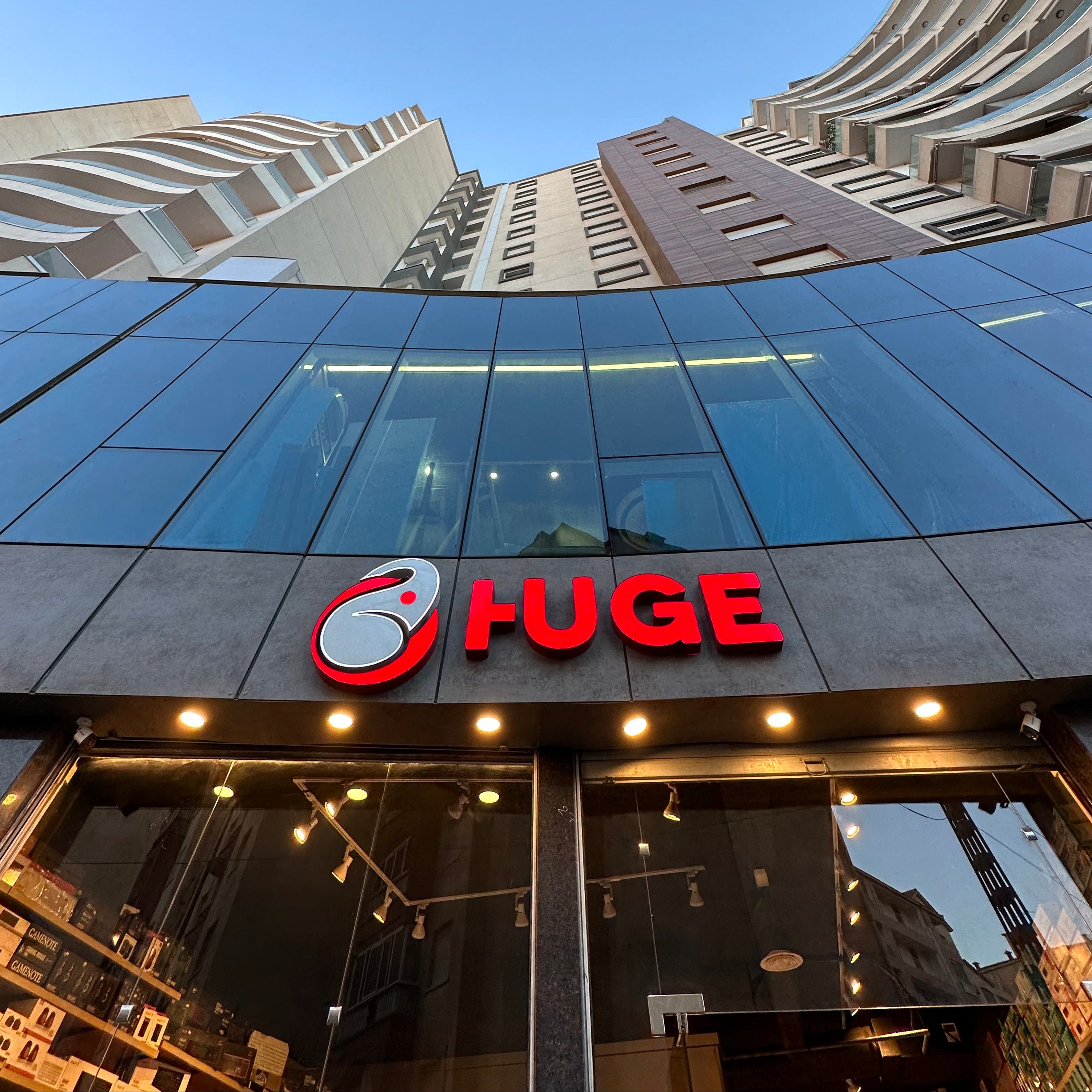 Building exterior with 'HUGE' logo and glass facade